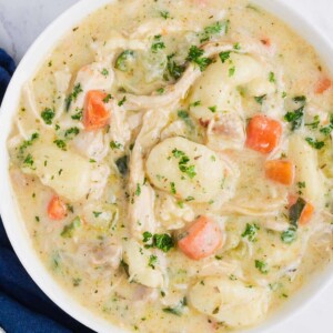 A white bowl full of Olive Garden's creamy chicken gnocchi soup made at home.