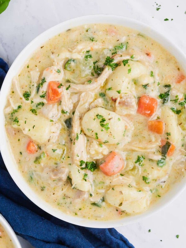 A white bowl full of Olive Garden's creamy chicken gnocchi soup made at home.