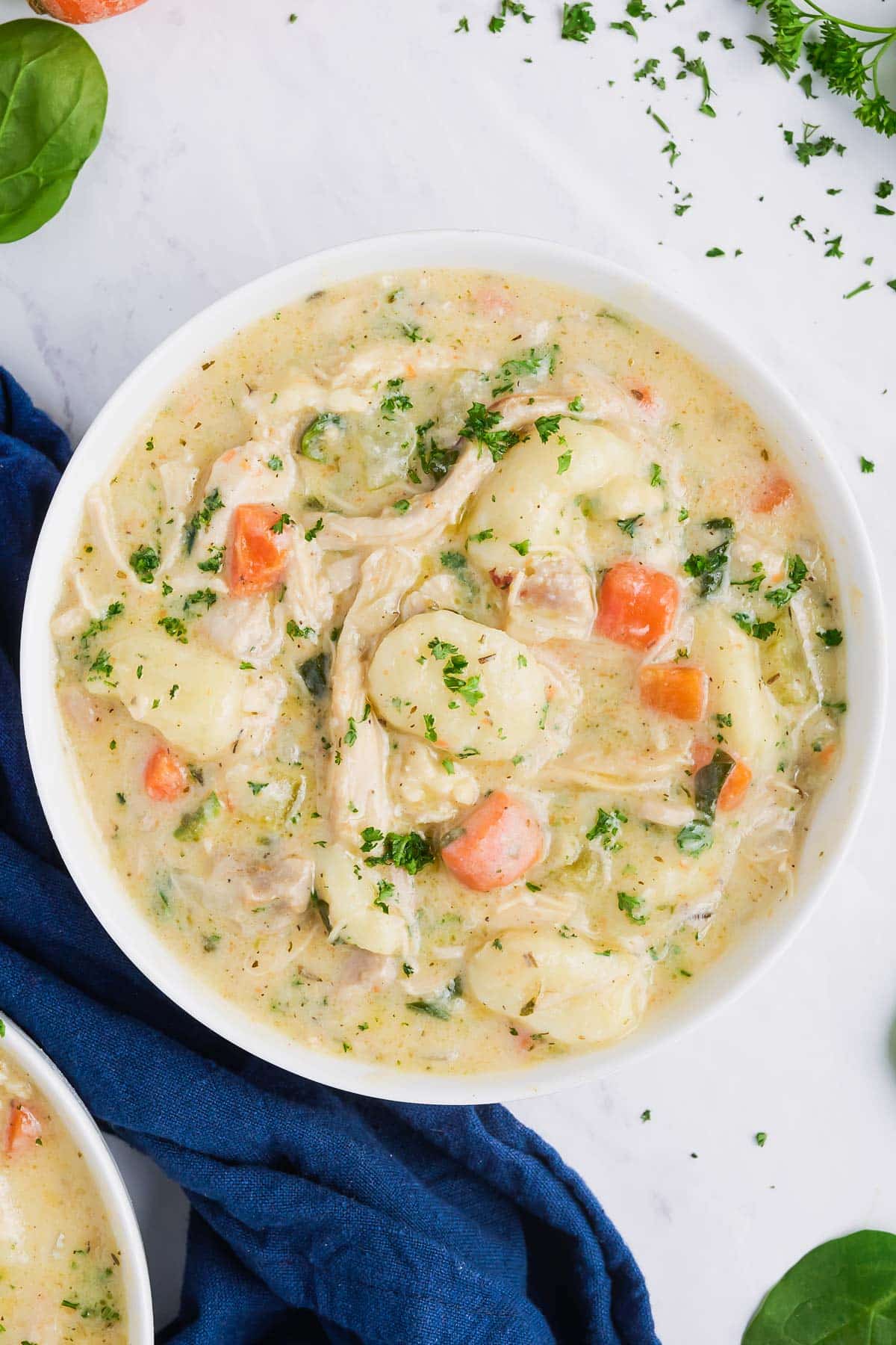 A white bowl full of Olive Garden's creamy chicken gnocchi soup made at home.