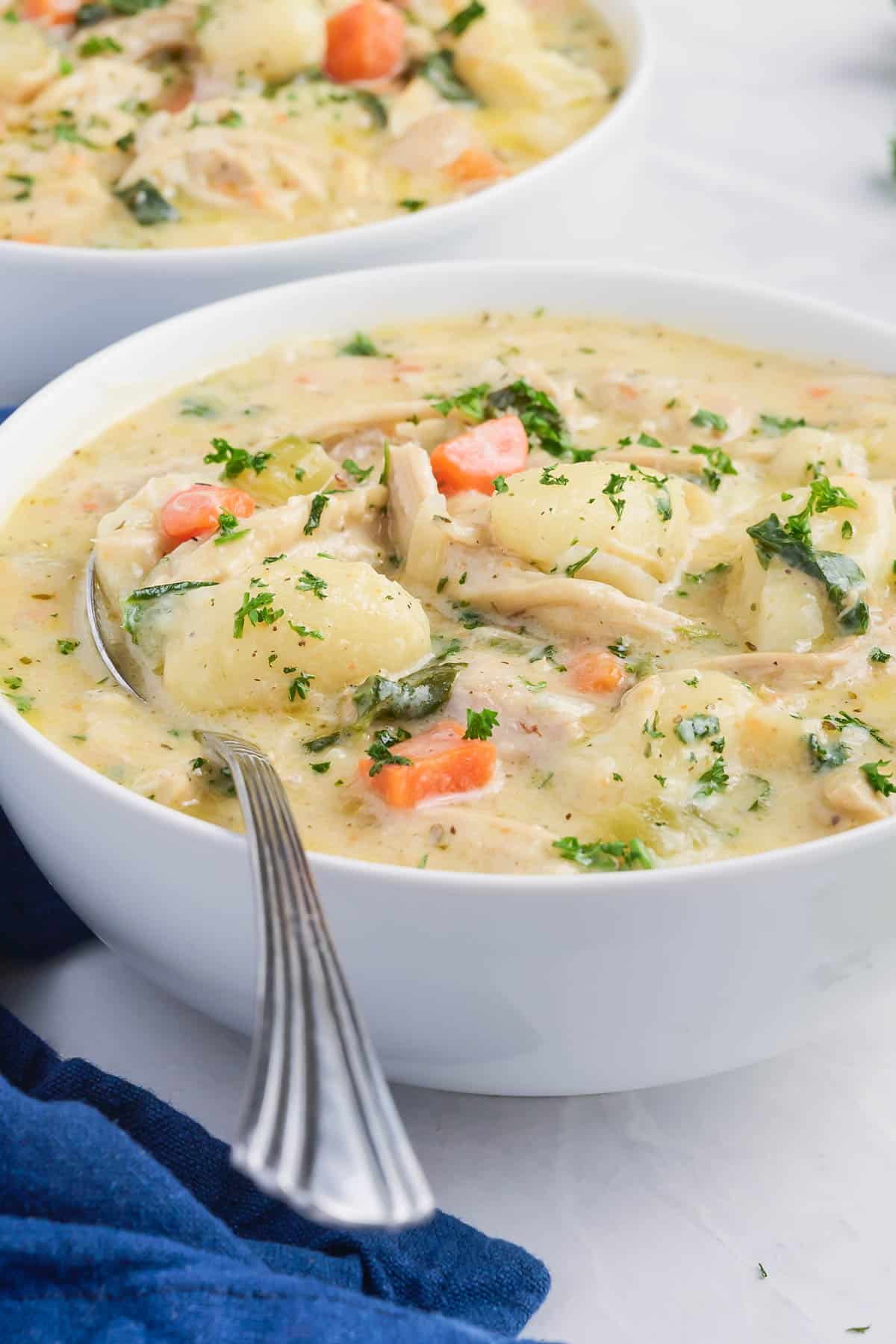 Olive Garden's Chicken Gnocchi Soup recipe is served in a white bowl with a spoon.