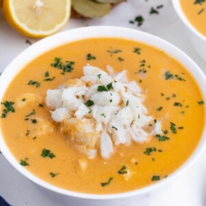 Creamy crab bisque is in a white bowl with jumbo lump crab meat on top.