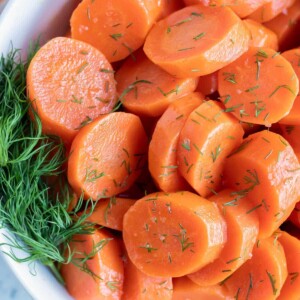 Sliced and seasoned boiled carrots are served in a white bowl.