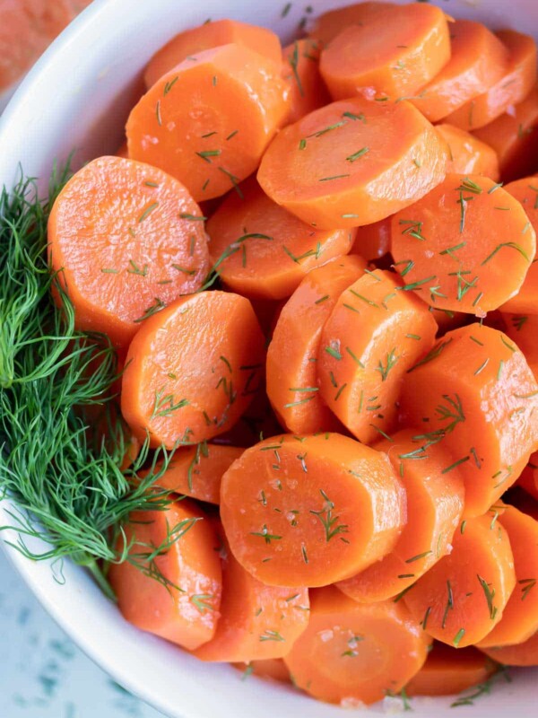 Sliced and seasoned boiled carrots are served in a white bowl.