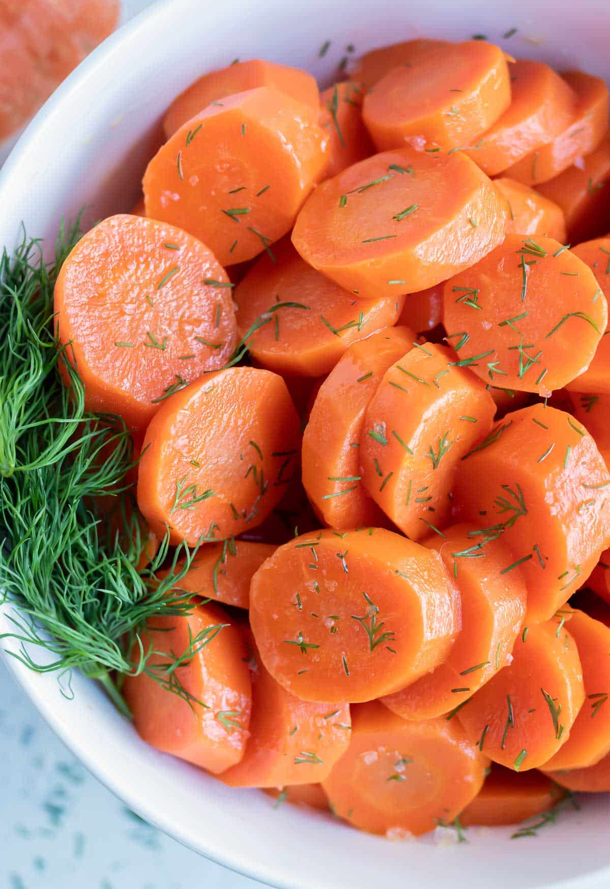 Sliced and seasoned boiled carrots are served in a white bowl.