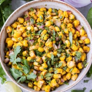 A white bowl full of a Chipotle Corn Salsa copycat recipe to be served as a dip with tortilla chips.