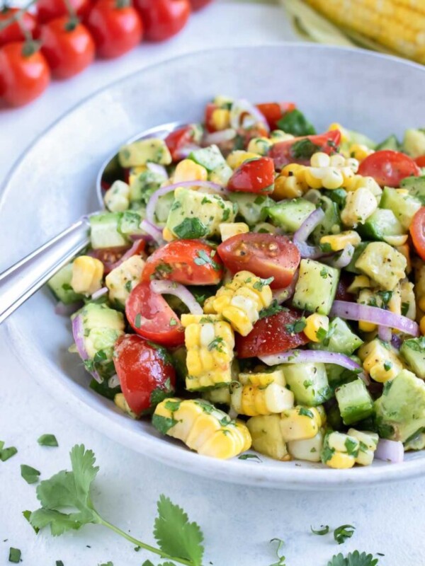A white bowl is used to hold the light and refreshing avocado corn salad.