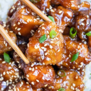 Homemade General Tsos Chicken is lifted up by chopsticks for an easy dinner.