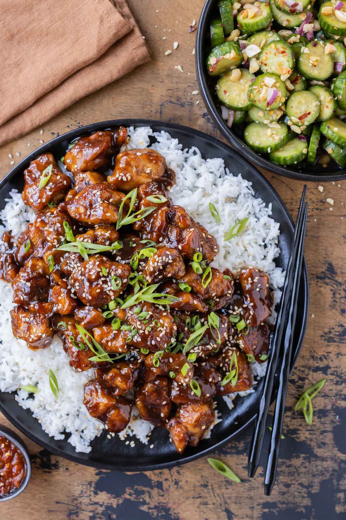 General Tso's Chicken is served over white rice with a side of spicy Asian cucumber salad for an easy weeknight dinner.