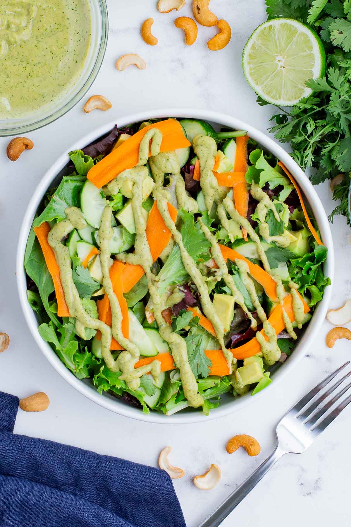 Spicy cashew dressing accompanies a bowl full of greens and vegetables.
