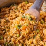 A restaurant-style Mexican rice recipe is in a stainless steel pot with a wooden spoon.