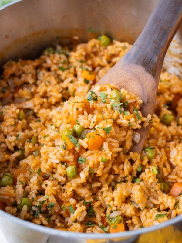 A restaurant-style Mexican rice recipe is in a stainless steel pot with a wooden spoon.