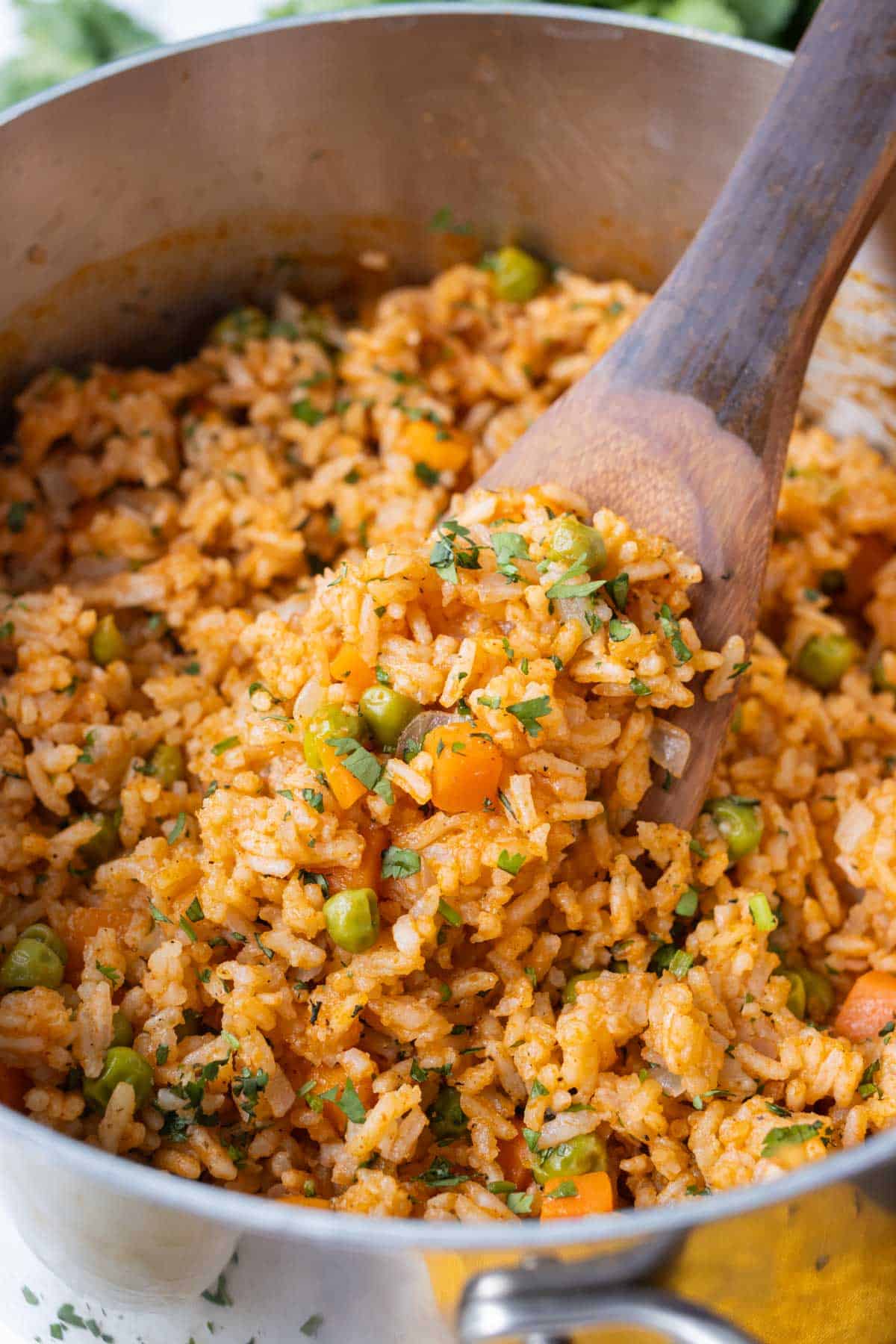 A restaurant-style Mexican rice recipe is in a stainless steel pot with a wooden spoon.