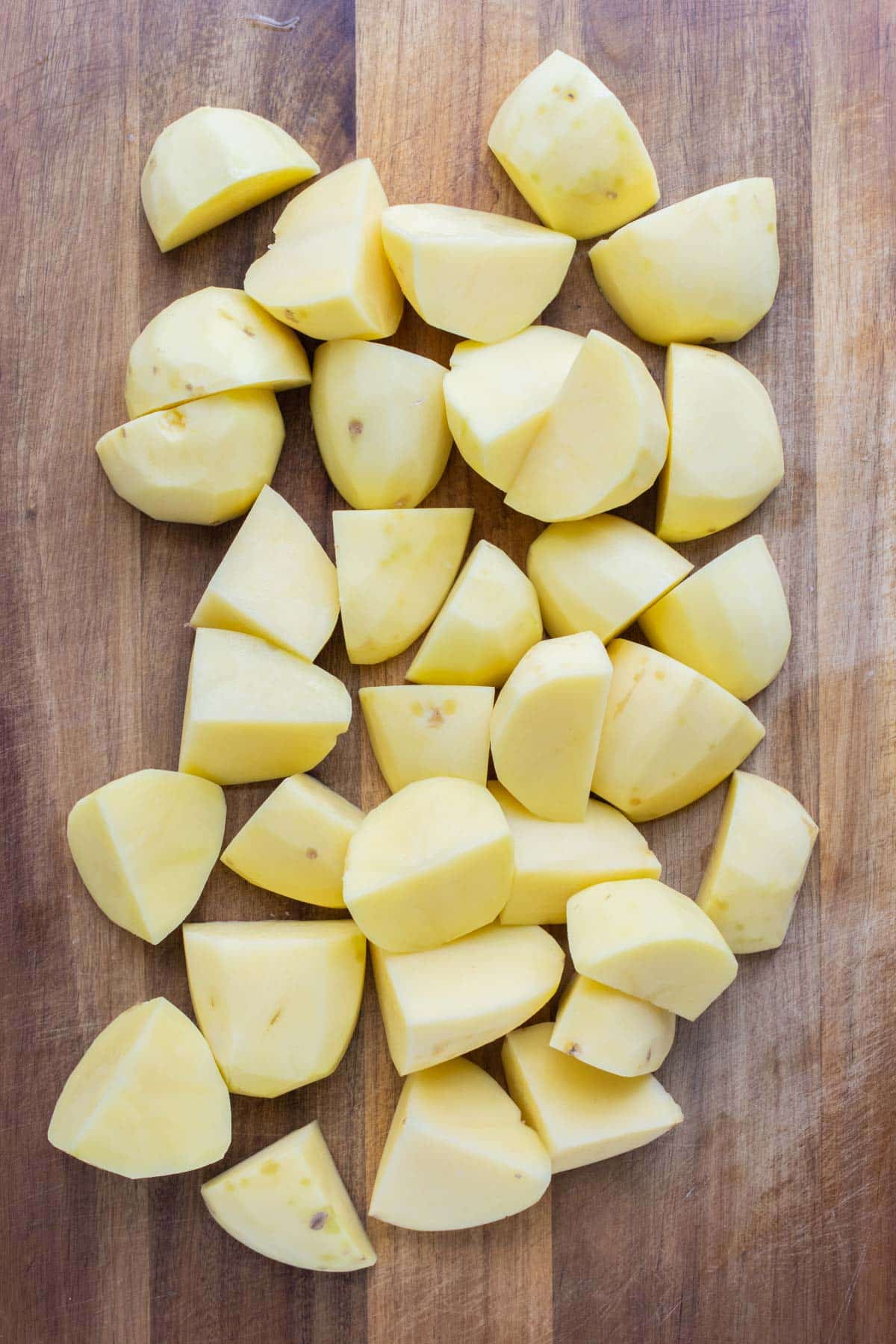 Peeled and cubed yukon gold potatoes on a cutting board.