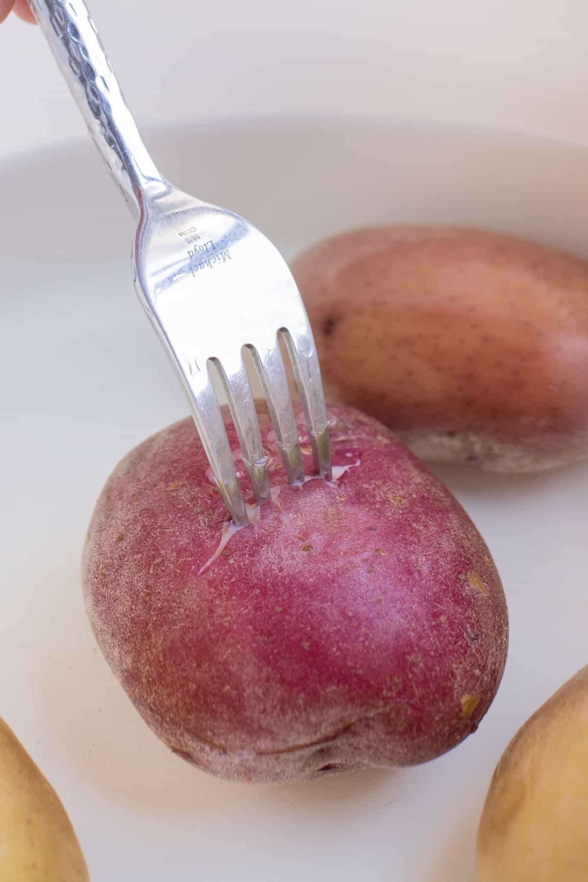 A fork piercing a boiled potato to show doneness.