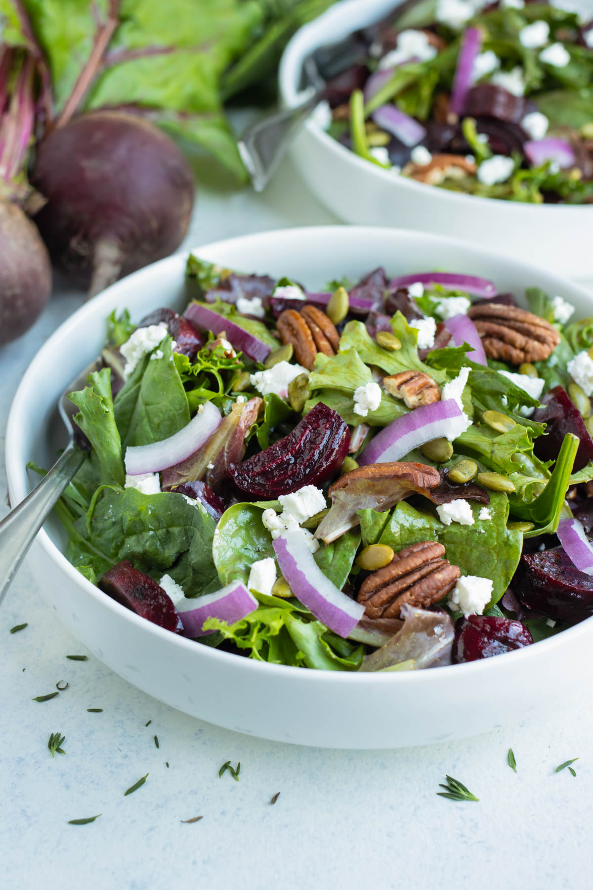 A white bowl is used to serve roasted beet salad with goat cheese.