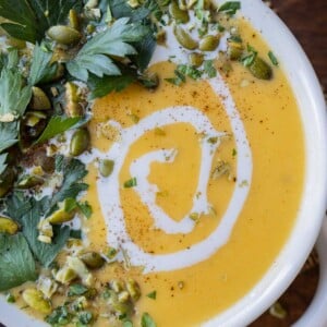 A bowl full of roasted butternut squash soup with a swirl of coconut milk.