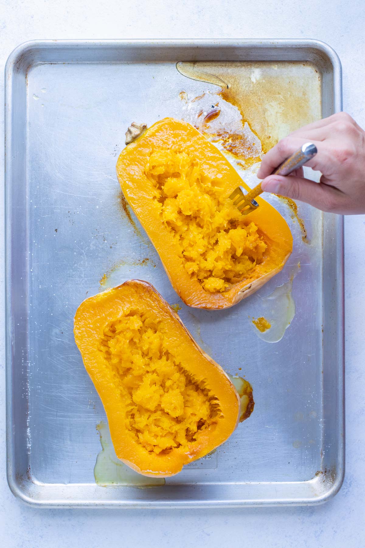 Roasted butternut squash is fluffed up with a fork.