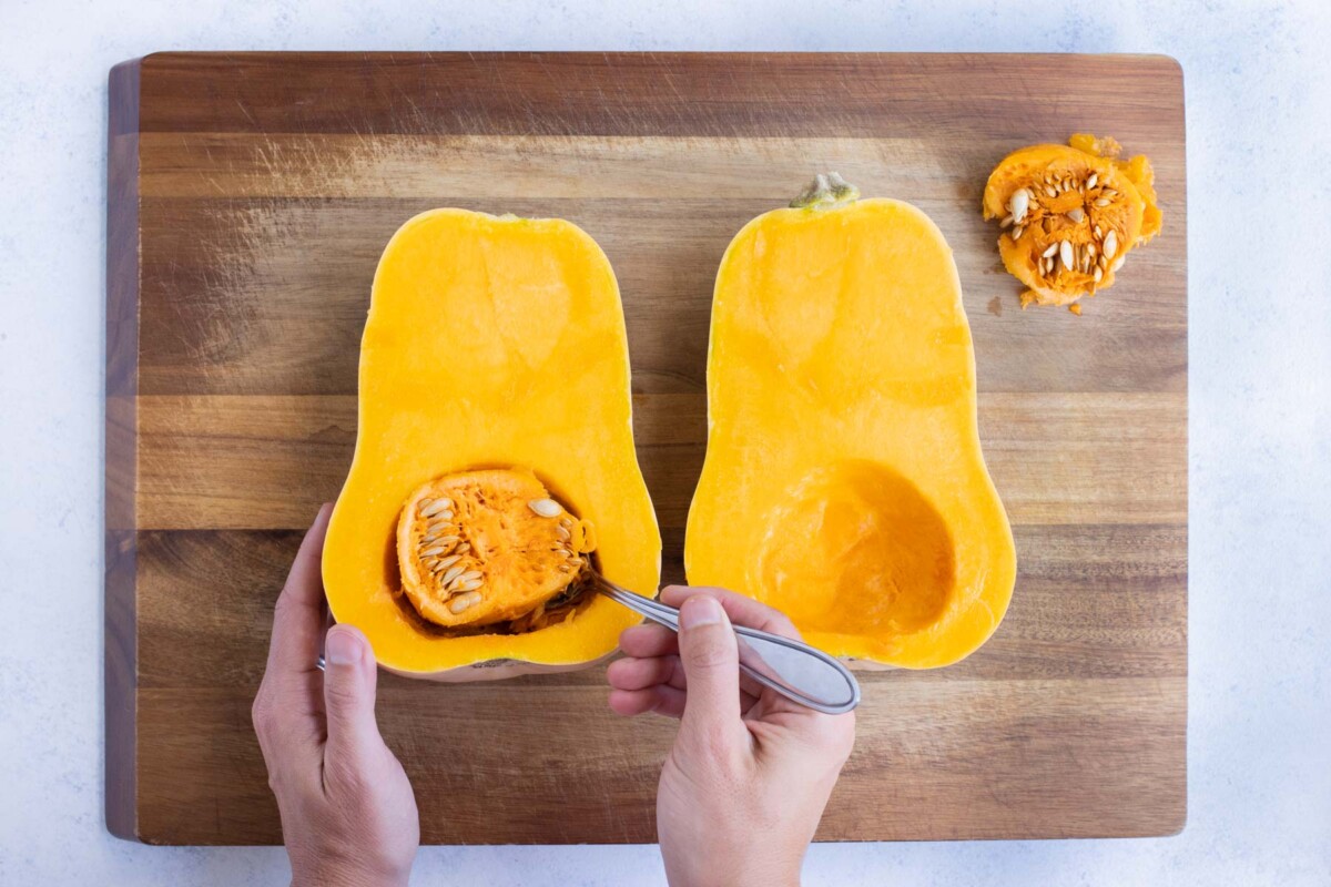 The seeds are spooned out of a butternut squash.