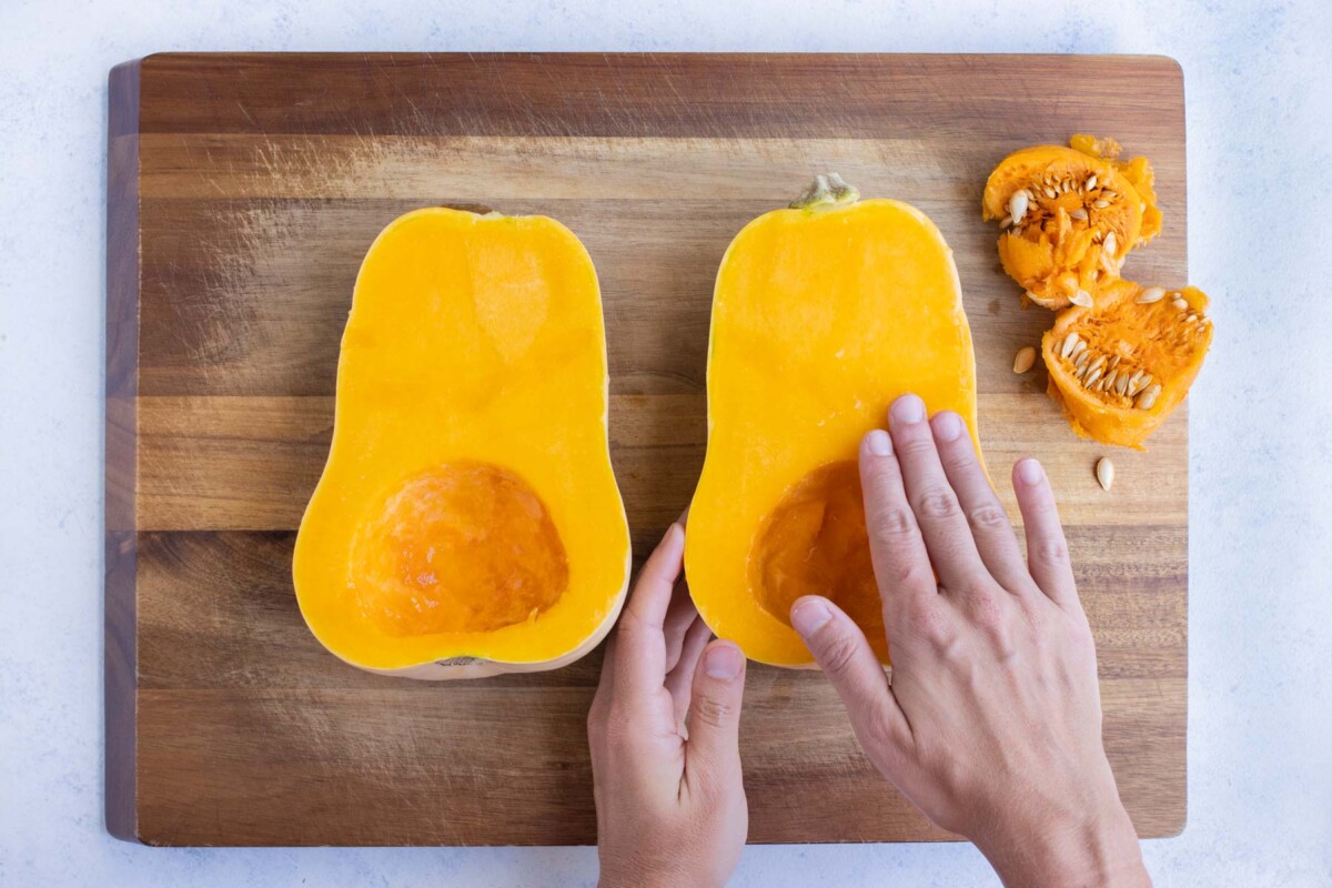 A butternut squash half is covered in oil and salt.