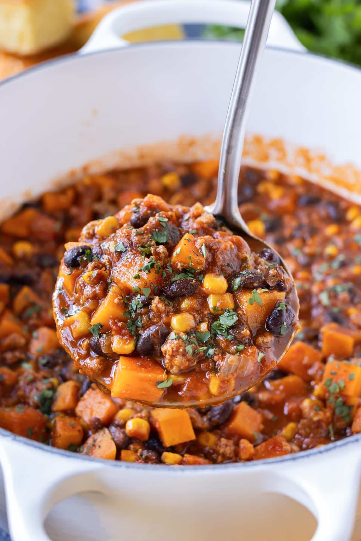 A ladleful of a healthy turkey chili recipe, cooked in a Dutch oven.