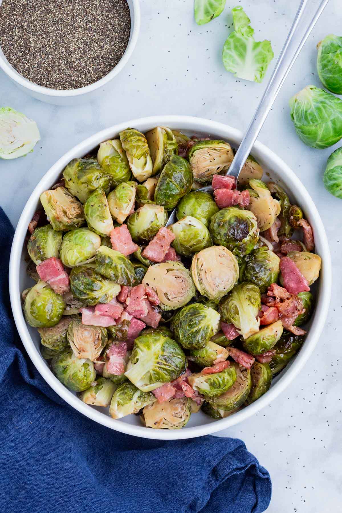 An overhead shot of Brussels sprouts baked with bacon in the oven and served in a white bowl.