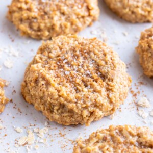 Almond butter oatmeal cookies are on a parchment paper lined baking sheet.