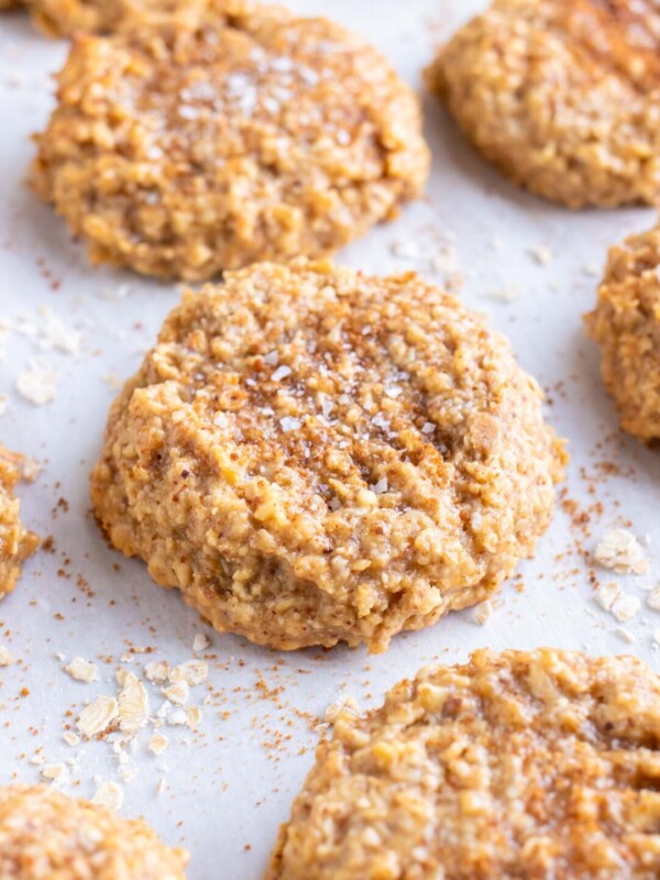 Almond butter oatmeal cookies are on a parchment paper lined baking sheet.