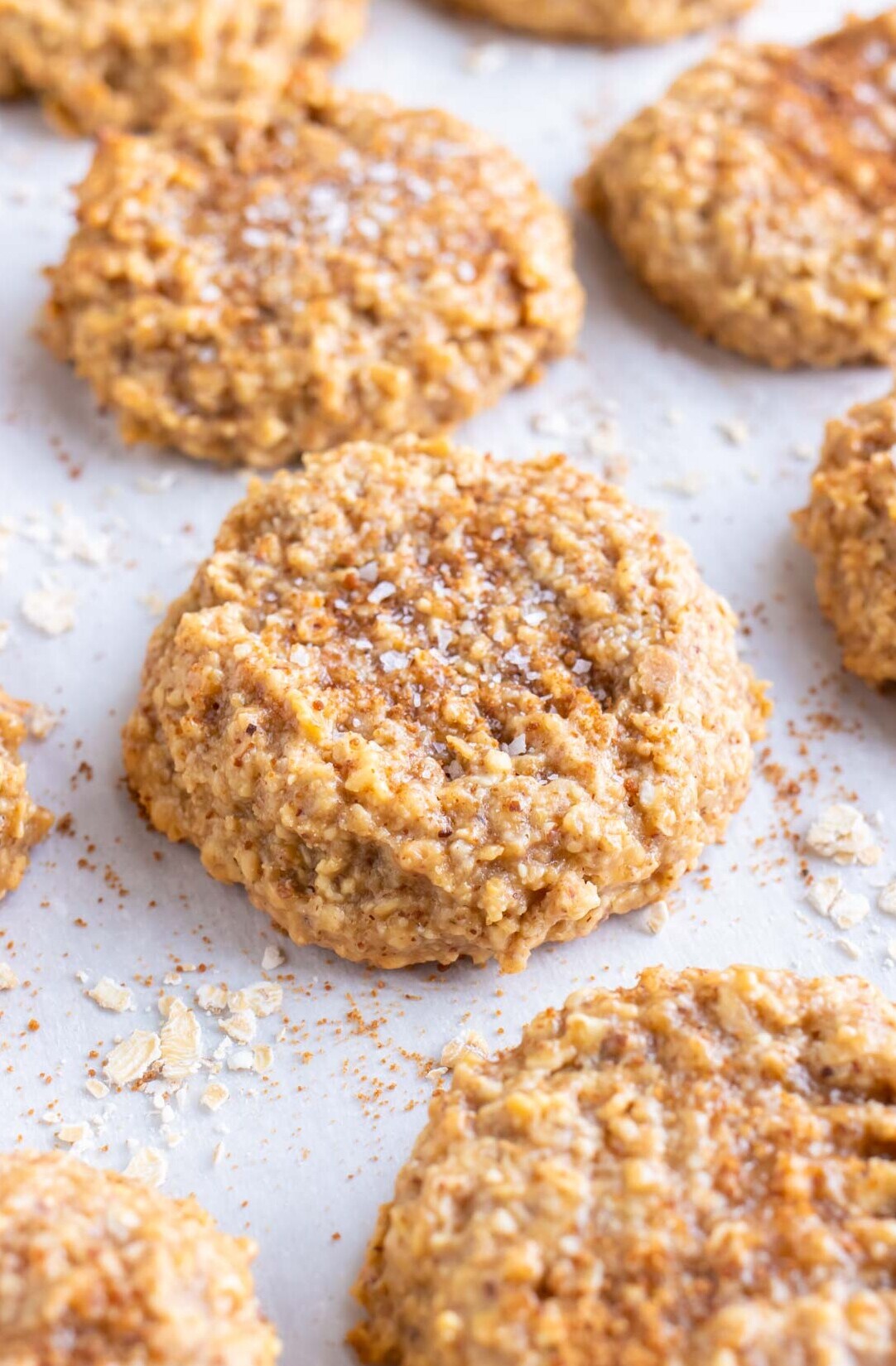 Almond butter oatmeal cookies are on a parchment paper lined baking sheet.