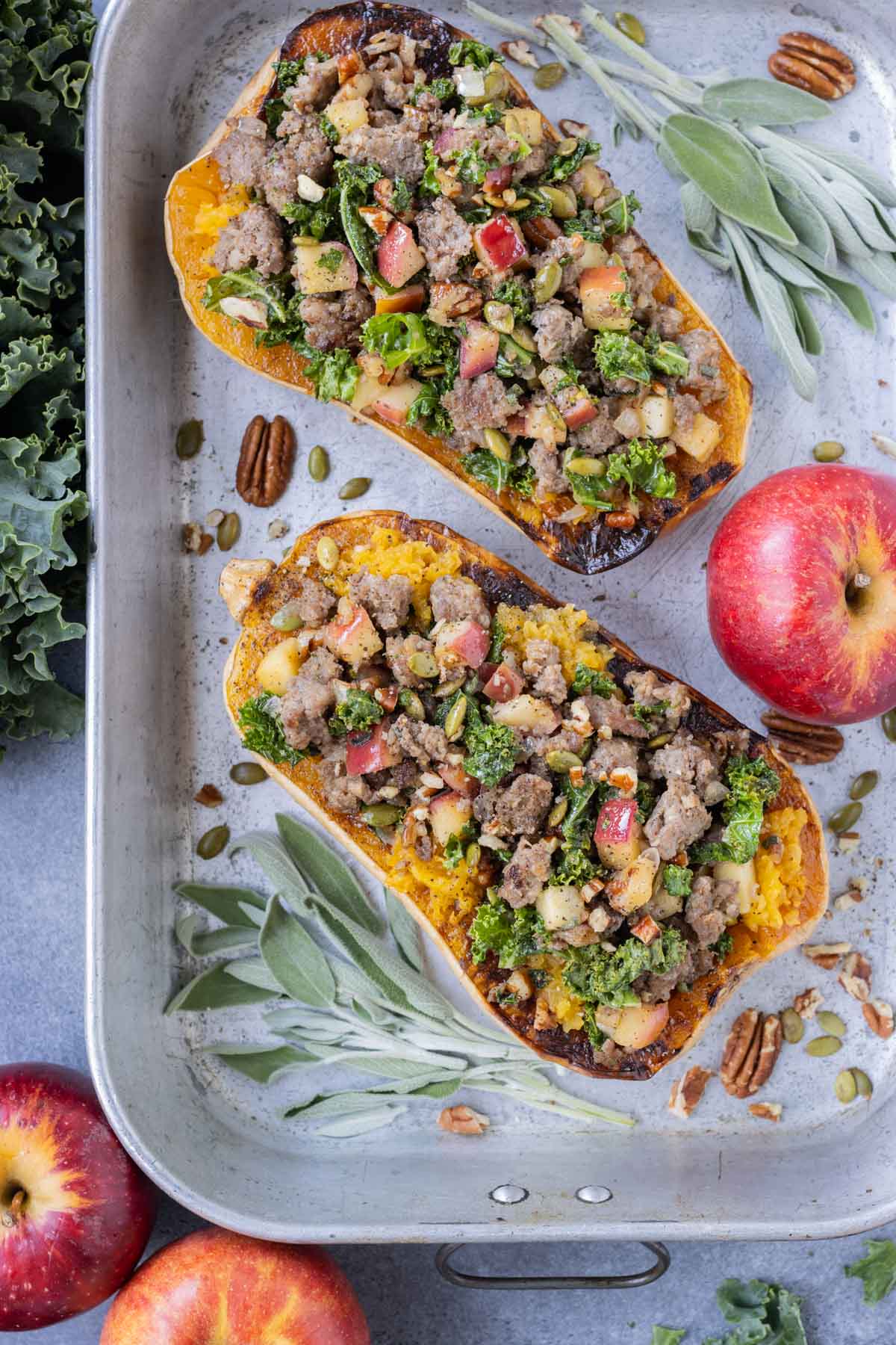 A sausage stuffed butternut squash recipe with apples, sage, and kale.