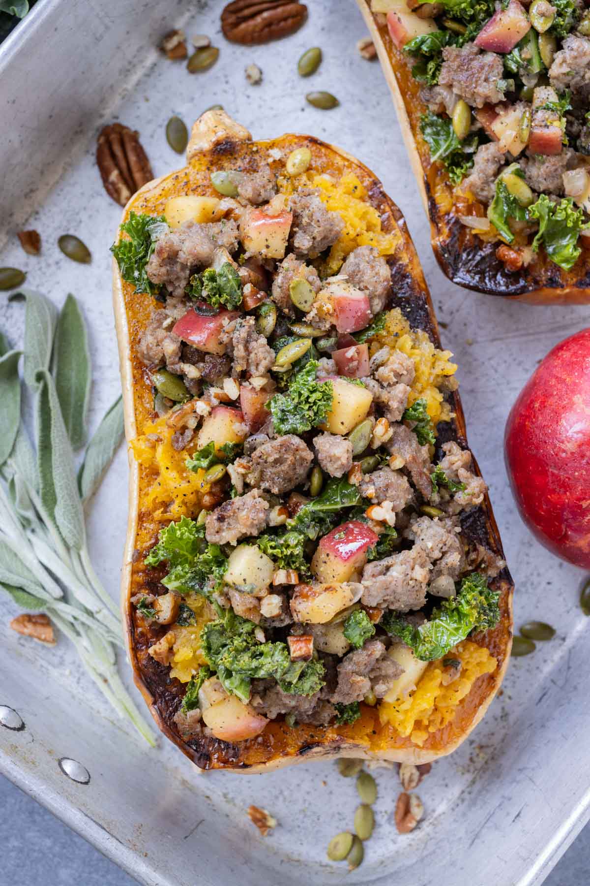 A stuffed butternut squash with ground sausage and kale in a baking dish.