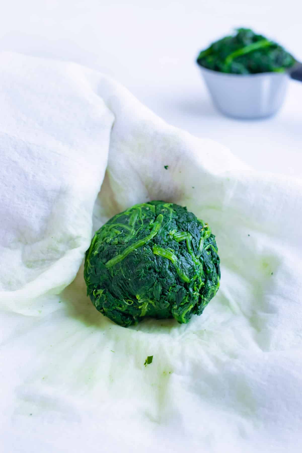 Moisture is squeezed from the spinach before measuring and adding to the filling recipe.