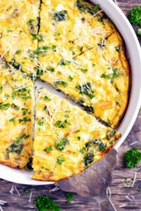 A slice of crustless quiche being picked up out of a baking dish.