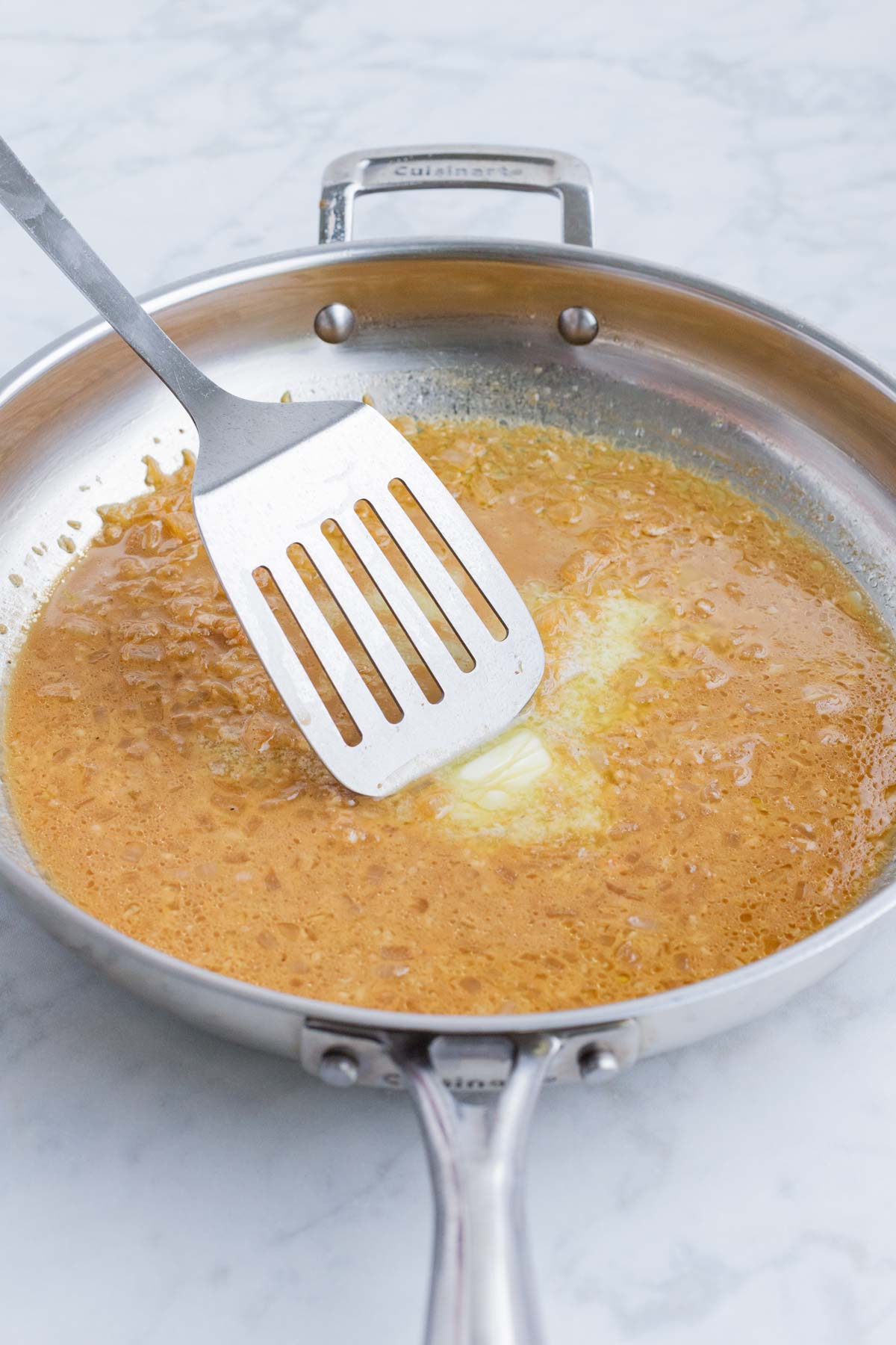 A spatula stirs the base of the sauce.