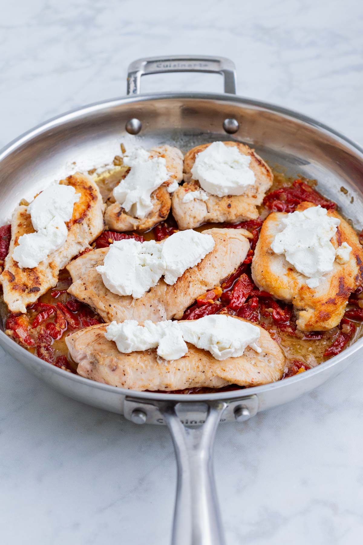 Chicken is returned to the pan and goat cheese is spooned on top.