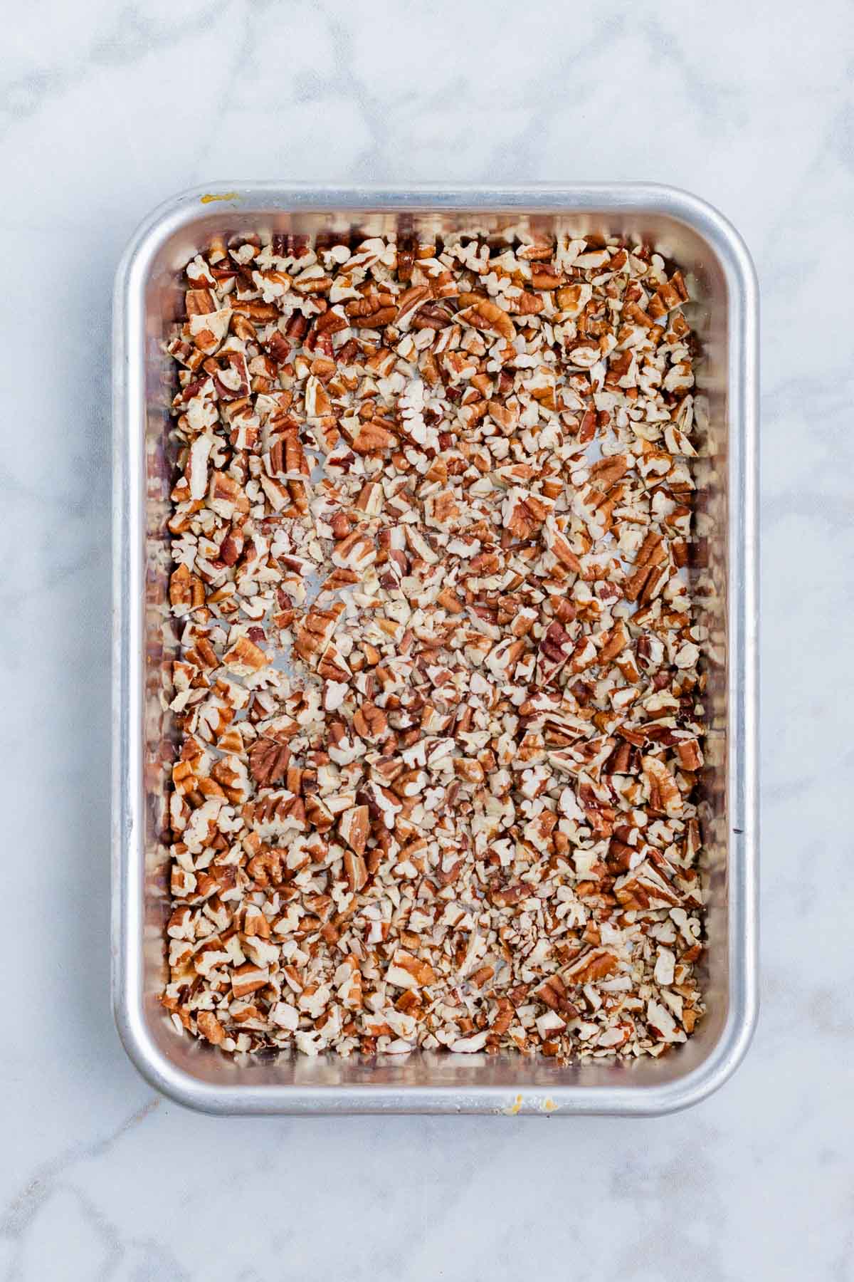 Chopped pecans are toasted in the oven.