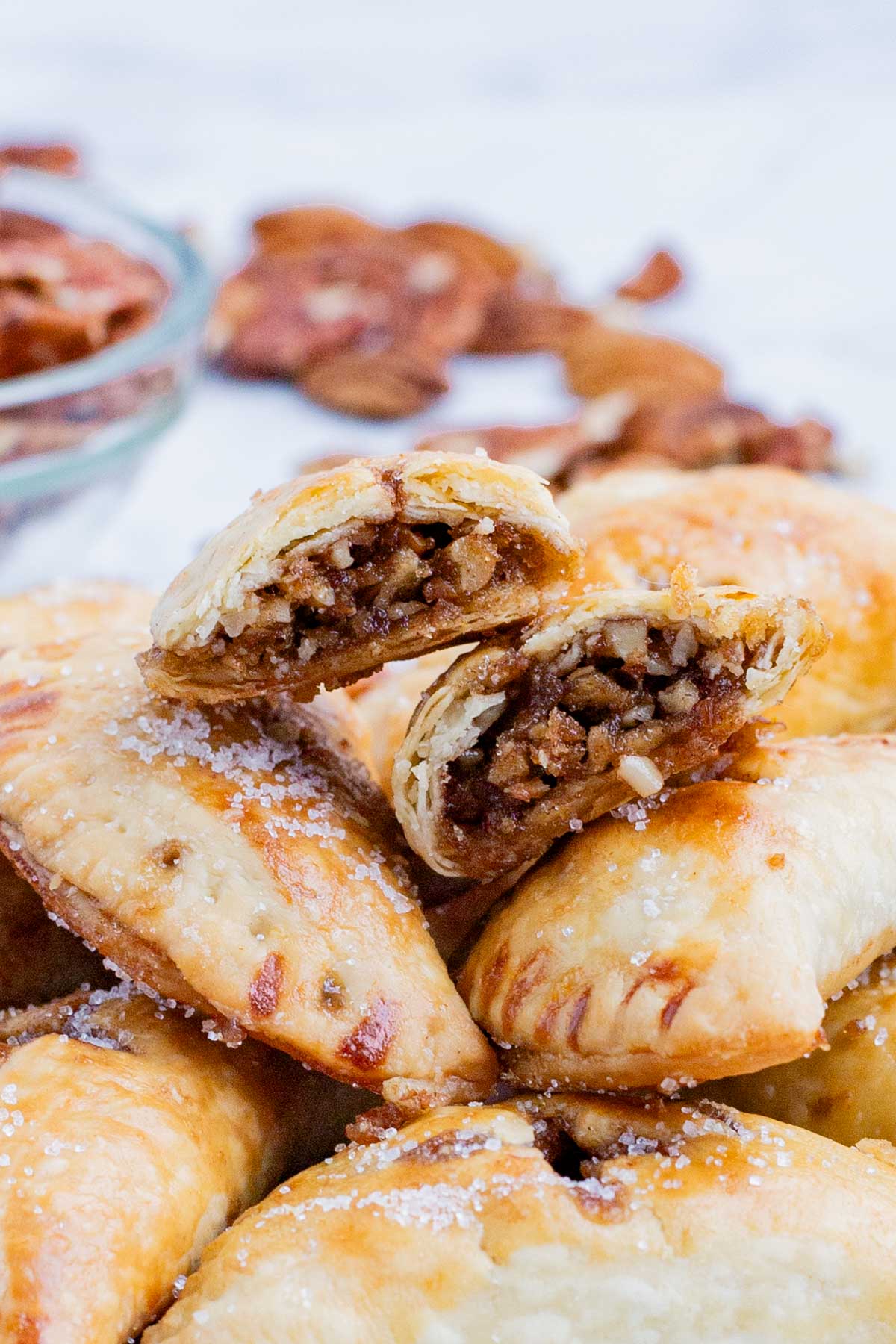 A pile of pecan hand pies with filling that is wrapped in a flaky crust is ready to serve.