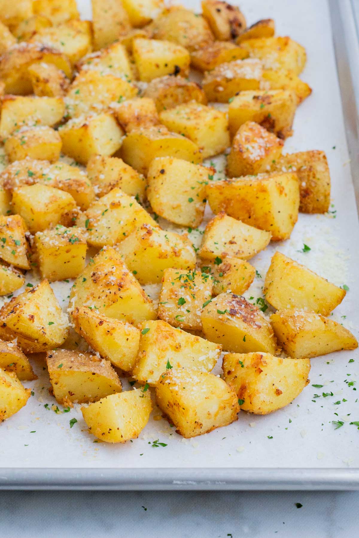 Roasted potatoes are sprinkled with fresh cheese and parsley.