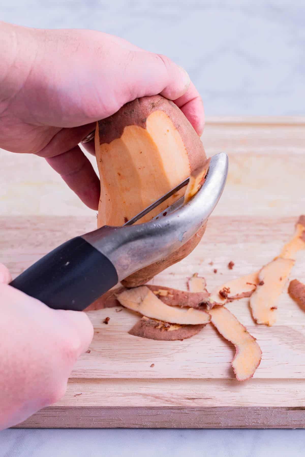 the skin of the sweet potato is removed with a vegetable peeler.