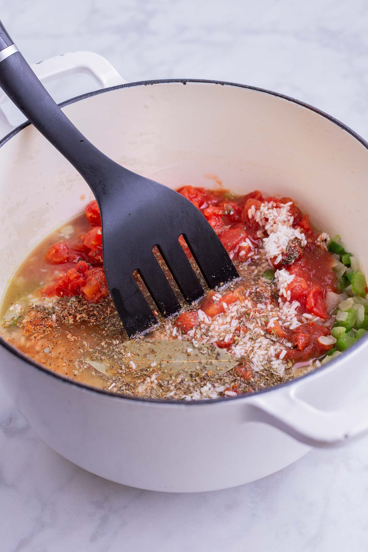 Rice and tomato paste and canned tomatoes are added to the pot.