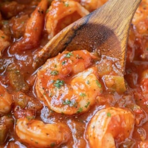 A wooden spoon scoops up a serving of New Orleans Shrimp Creole from a Dutch oven.