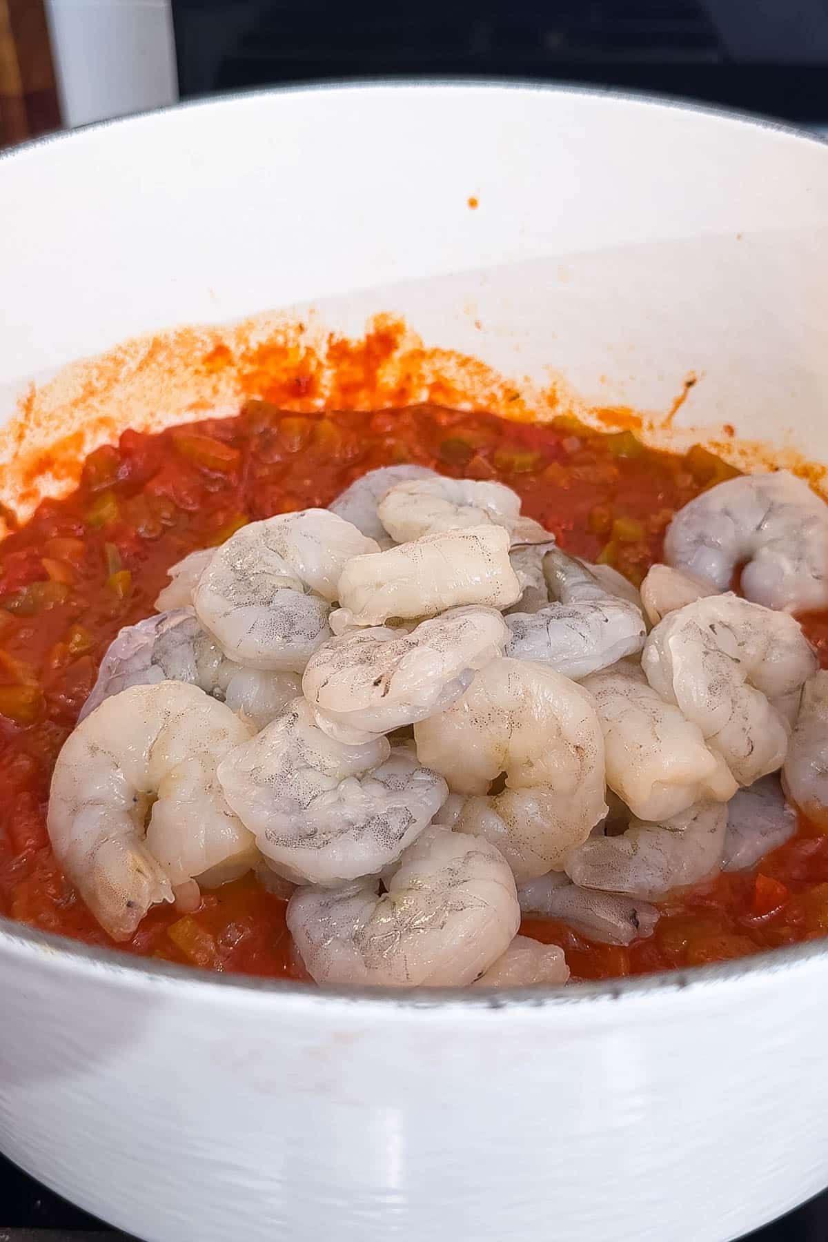 Shrimp are added into a tomato based sauce for a shrimp creole recipe.