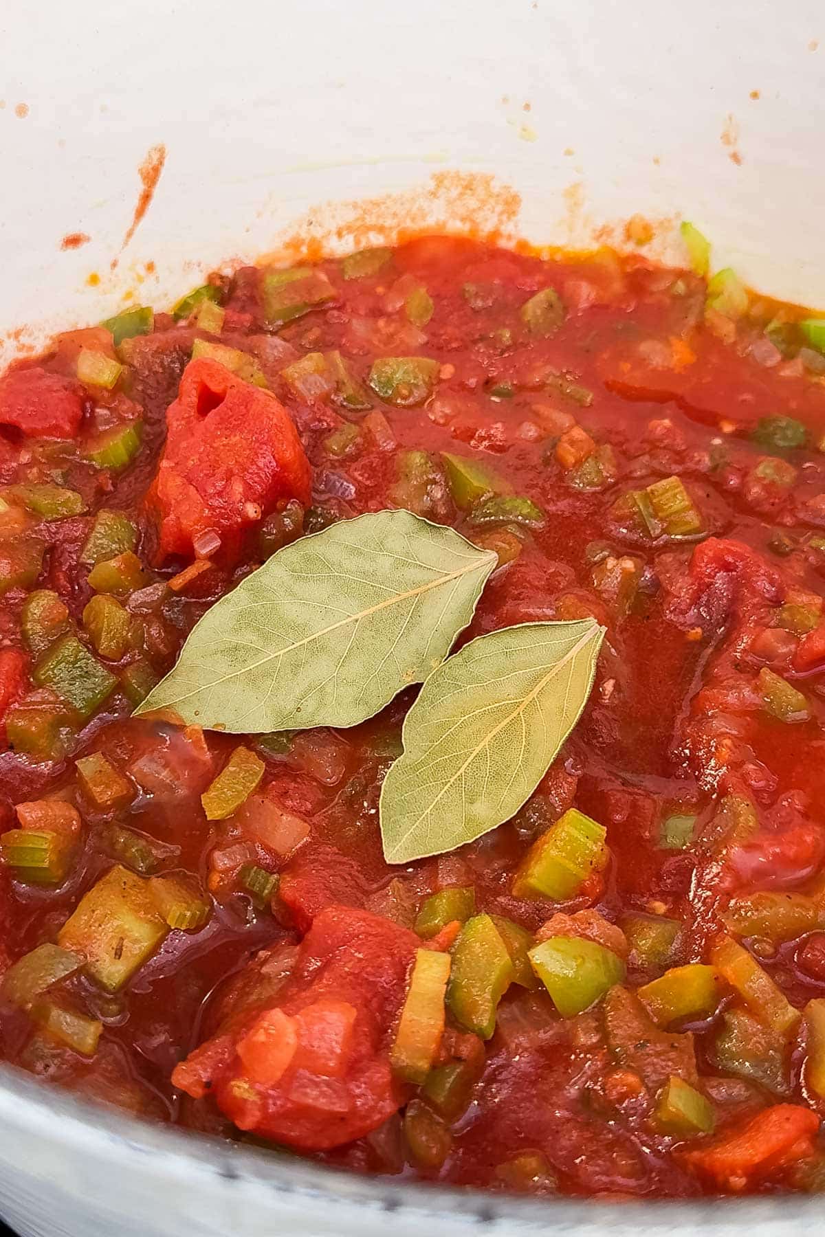 Bay leaves are added to a pot full of a shrimp creole recipe.