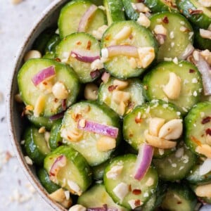 A spicy Asian cucumber salad with crushed peanuts and red onion in a serving bowl.