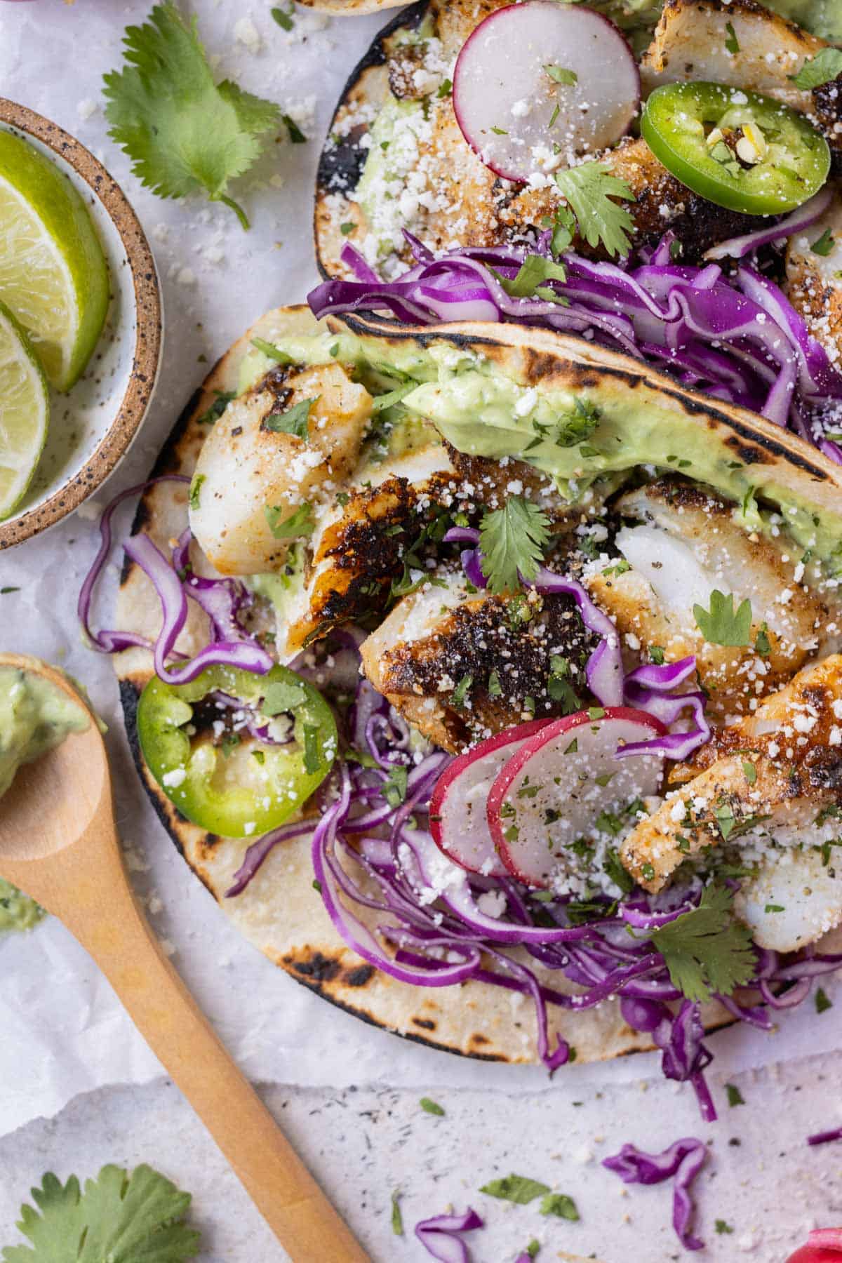 A blackened fish taco recipe that is served with a homemade avocado sauce and topped with shredded cabbage.