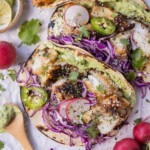 A blackened fish taco recipe that is served with a homemade avocado sauce and topped with shredded cabbage.