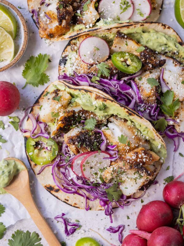 A blackened fish taco recipe that is served with a homemade avocado sauce and topped with shredded cabbage.