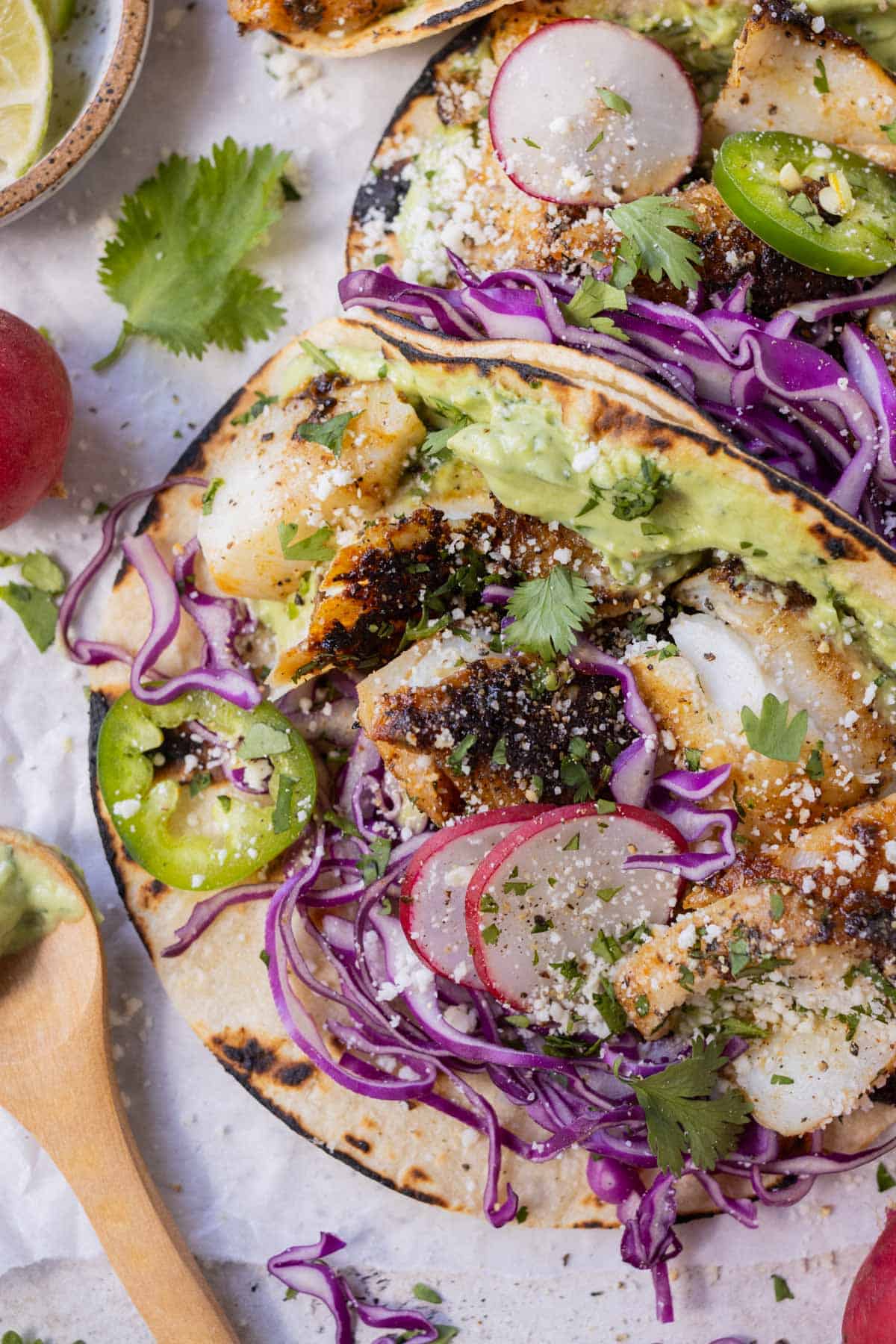 A blackened fish taco recipe that is served with a homemade avocado sauce and topped with shredded cabbage.