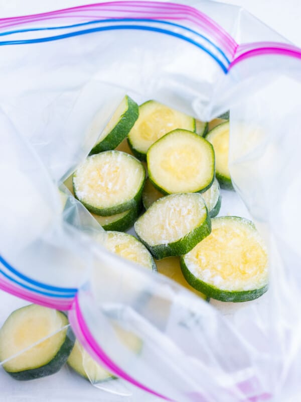 Frozen zucchini is added to a ziplock storage bag to use in future recipes.