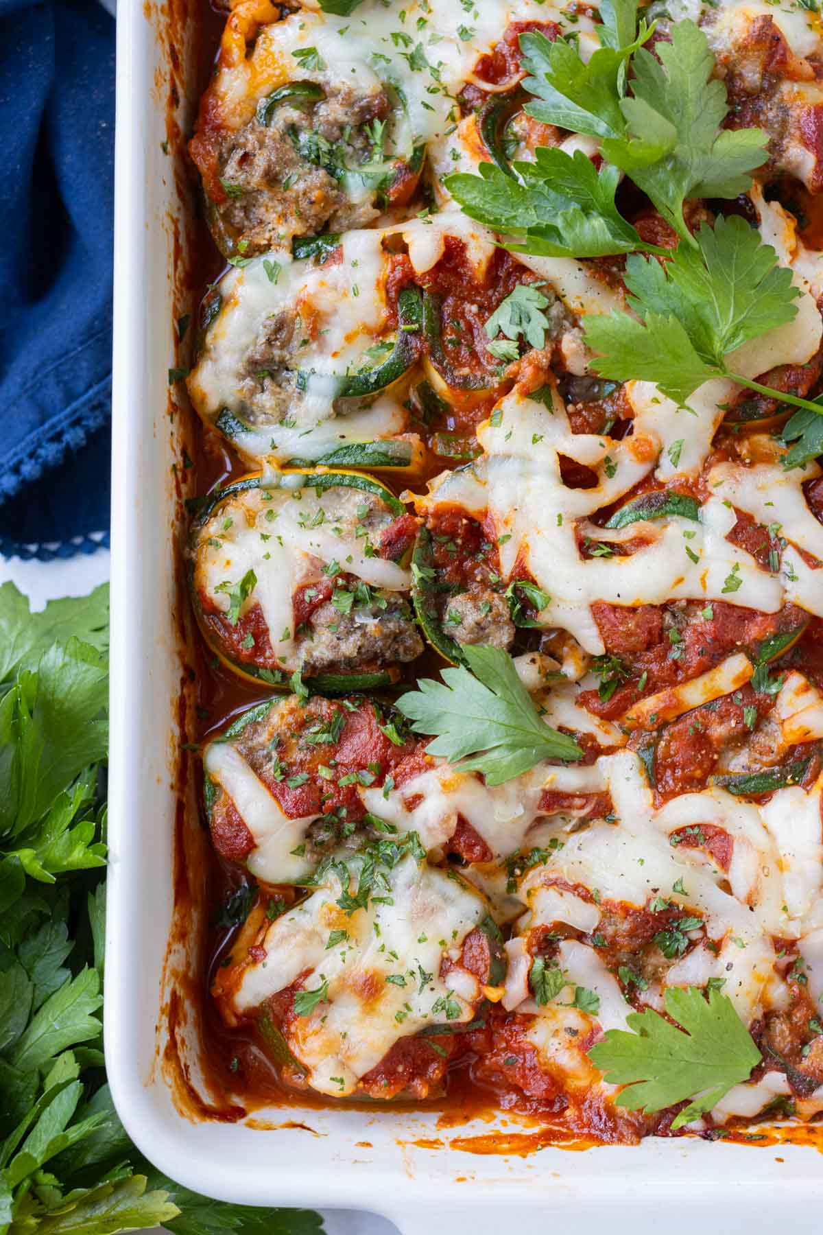 Easy zucchini lasagna roll-ups in red sauce garnished with herbs.