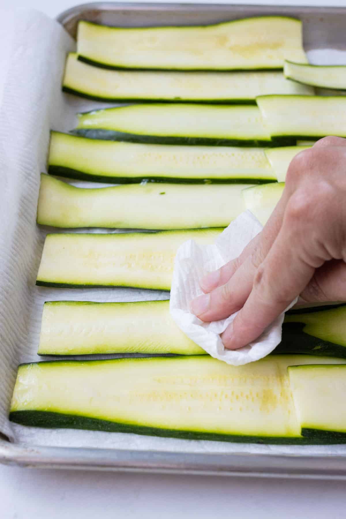 A paper towel dabs zucchini as water seeps out.